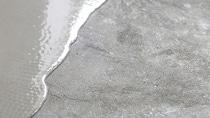 A smooth layer of wet concrete is spreading over a rough, dry concrete surface. A smooth layer of wet concrete is spreading over a rough, dry concrete surface.