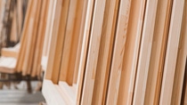 Stacks of light wooden panels are neatly arranged vertically in a workshop.