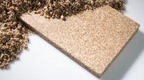 Half of the picture shows sawdust or small pieces of wood, and underneath a sheet of plywood appears. 