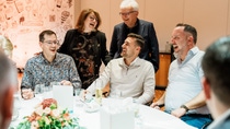 A group of five people laughing and enjoying a lively conversation around a white table in Feierabendhaus, Ludwigshafen.