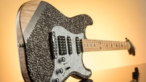 Shot of a dark stratocaster shaped electric guitar in front of a sundowning background. Surface of the guitar's body is made of coffee beans. Shot of a dark stratocaster shaped electric guitar in front of a sundowning background. Surface of the guitar's body is made of coffee beans.