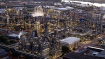 Low-carbon steam production facility at a large industrial plant complex along a river, aerial view at dusk.