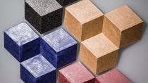 Colorful 3D cubes in black, beige, blue, and pink form a geometric pattern against a gray background.