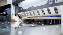 Close-up of a shiny industrial sheet cutter with a sharp blade and metal components. Close-up of a shiny industrial sheet cutter with a sharp blade and metal components.