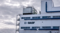 Industrial building (Hamina production builduing) with BASF logo, gray sky backdrop, and a red windsock indicating wind direction. Industrial building (Hamina production builduing) with BASF logo, gray sky backdrop, and a red windsock indicating wind direction.