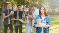 Title photo for March edition of the BASF Resins & Additives Newsletter for Printing & Packaging. A woman holding take-away food packaging made with coated paper