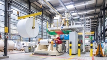 Spacious industrial paper mill interior with large rolls of white paper on machines. Bright lighting and modern equipment convey efficiency and precision. Spacious industrial paper mill interior with large rolls of white paper on machines. Bright lighting and modern equipment convey efficiency and precision.