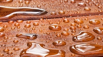 Wet wooden surface with scattered water droplets reflecting light. The rich brown wood grain contrasts with the shiny, smooth droplets. Wet wooden surface with scattered water droplets reflecting light. The rich brown wood grain contrasts with the shiny, smooth droplets.