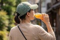 Woman drinking from a PET bottle containing orange juice and featuring a high-quality transparent label. This image was generated with AI. 