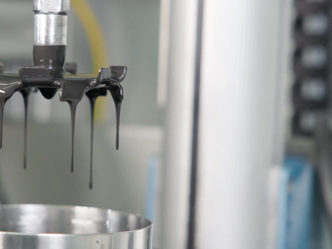 Close-up of black liquid dripping from a metal nozzle into a shiny metal container, in an industrial setting, conveying precision and focus. Close-up of black liquid dripping from a metal nozzle into a shiny metal container, in an industrial setting, conveying precision and focus.