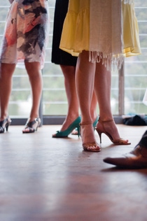 Women's legs in dresses and high heels are seen from the knee down on a wooden floor, creating a sense of elegance and social gathering. Women's legs in dresses and high heels are seen from the knee down on a wooden floor, creating a sense of elegance and social gathering.