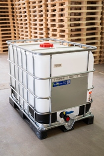 The image shows an industrial C-IBC packaging for the storage and transport of liquid substances. It consists of a plastic container in a steel cage. 