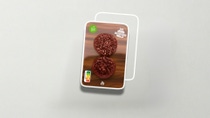 Flat laminated paper packaging containing two burger patties. 
