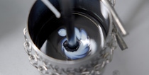 Close-up of a metal container with swirling black and white paint being mixed. It shows the anode slurry mixing process. Close-up of a metal container with swirling black and white paint being mixed. It shows the anode slurry mixing process.