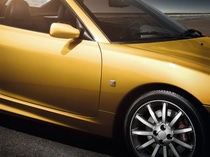 Close-up of a sleek yellow sports car with a shiny finish, highlighting the front wheel and mirror. Close-up of a sleek yellow sports car with a shiny finish, highlighting the front wheel and mirror.