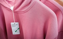 A close-up of two pink knit sweaters on hangers with a tag reading "FiberMax, CSF". A close-up of two pink knit sweaters on hangers with a tag reading "FiberMax, CSF".